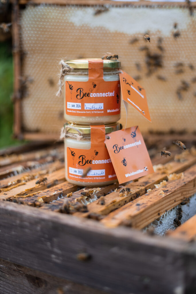 Zwei gestapelte „beeconnected“-Honiggläser auf einem Bienenkasten, gestaltet im Corporate Design